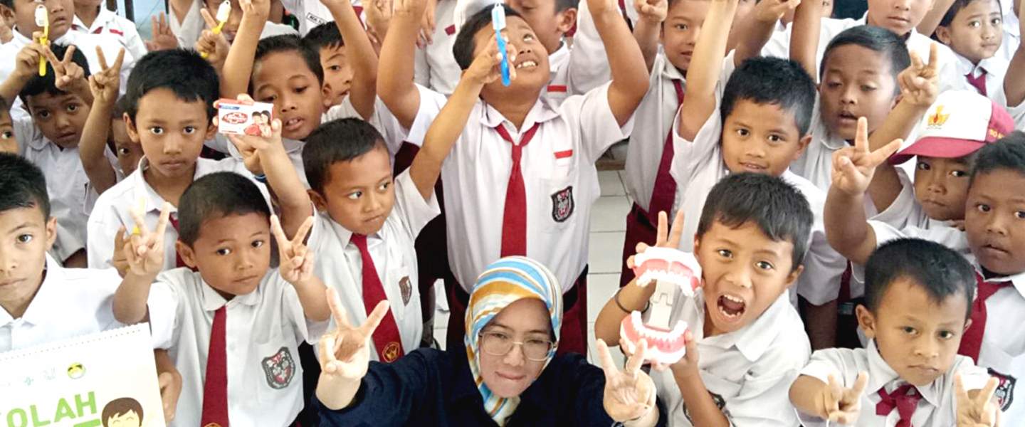 Anak-anak sekolah memegang pasta gigi dan sikat gigi di tangan mereka